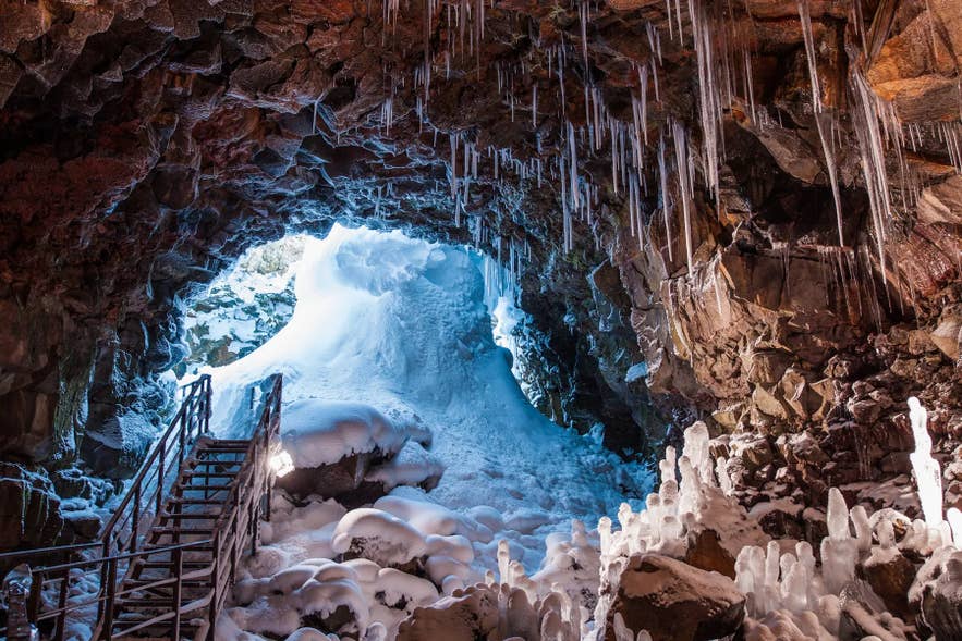 Inside Raufarholshellir lava cave with icicles and snow-covered rock formations. Inside Raufarholshellir lava cave with icicles and snow-covered rock formations.