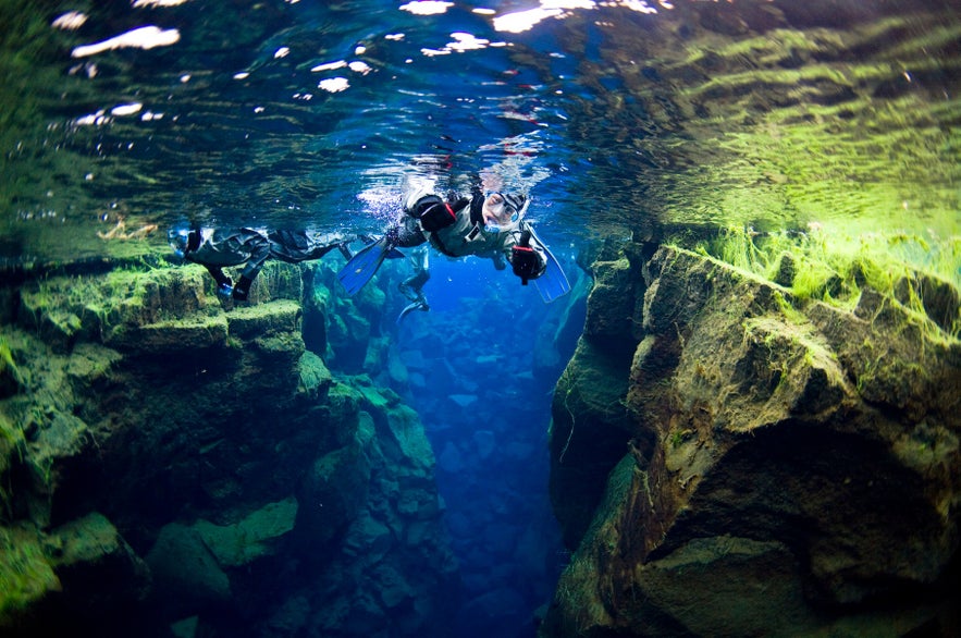 Snorkeling between tectonic plates in the clear waters of Silfra fissure in Iceland.