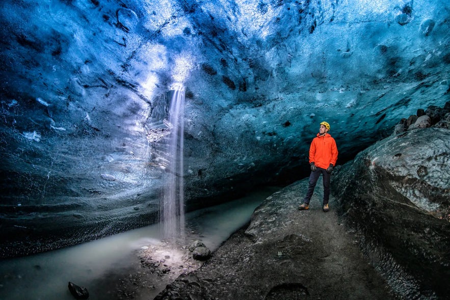 A visitor standing inside a blue ice cave beneath Vatnajokull glacier in Iceland.