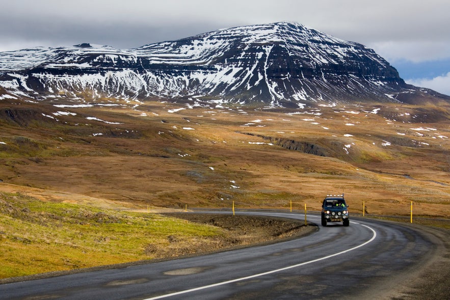 A 4x4 vehicle driving along a mountain road near Seydisfjordur in East Iceland.