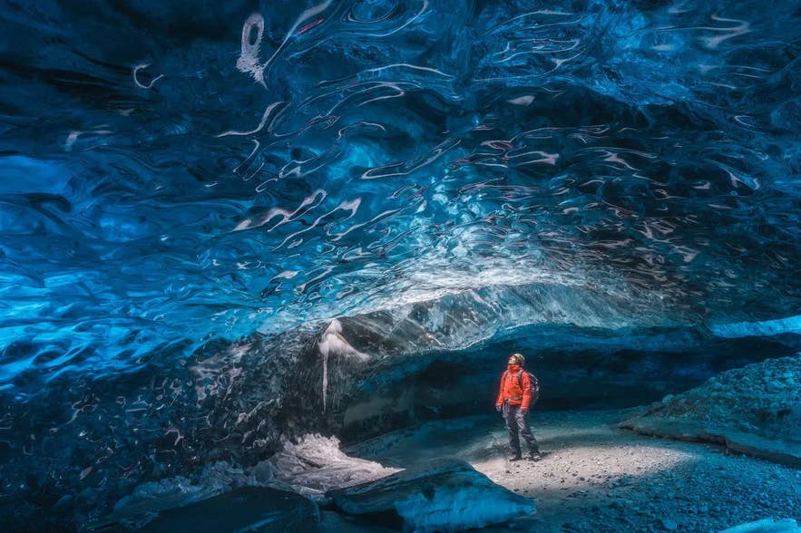 A person inside a natural blue ice tunnel formed within an Icelandic glacier. A person inside a natural blue ice tunnel formed within an Icelandic glacier.