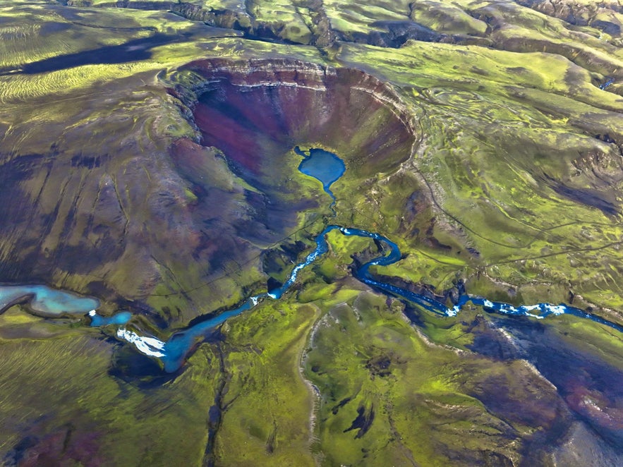 Aerial view of Rauðibotn volcanic crater in Iceland Highlands, with colorful slopes, crater lake, and winding glacial river. Aerial view of Rauðibotn volcanic crater in Iceland Highlands, with colorful slopes, crater lake, and winding glacial river.