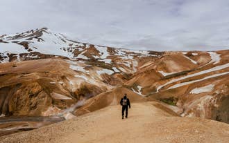 Hiker walking along a dusty ridge in the colorful rhyolite mountains of Kerlingarfjoll.