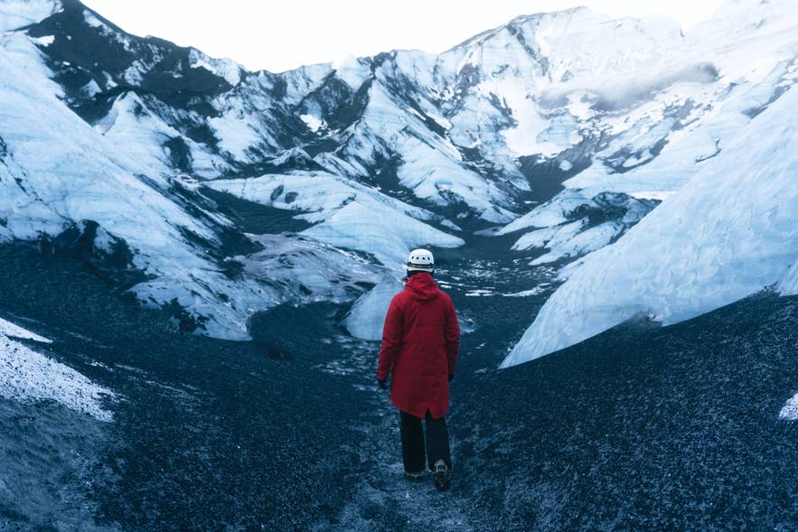 Traveler in a red jacket standing inside an ice canyon on Myrdalsjokull Glacier. Traveler in a red jacket standing inside an ice canyon on Myrdalsjokull Glacier.