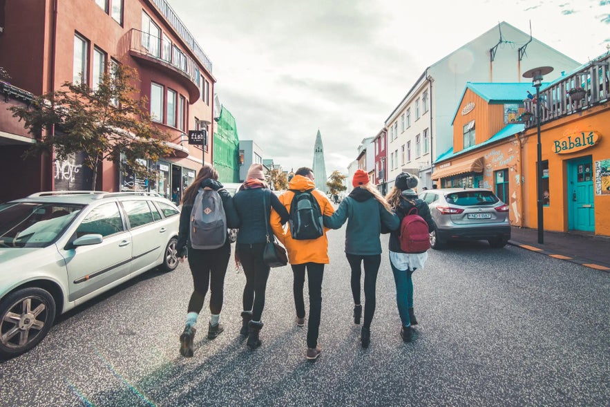 Five people stroll together through a vibrant Reykjavik street, with Hallgrimskirkja rising ahead.