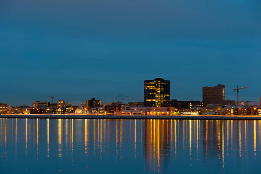 Lo skyline di Reykjavik riflesso sull’acqua al tramonto lungo il lungomare.