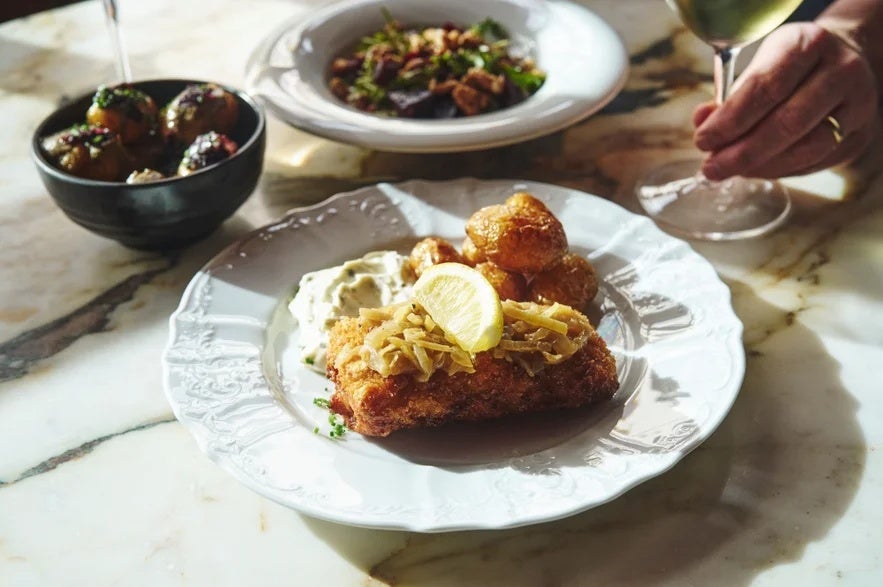 A plate of Icelandic fish with potatoes and sauce is served at a restaurant table.