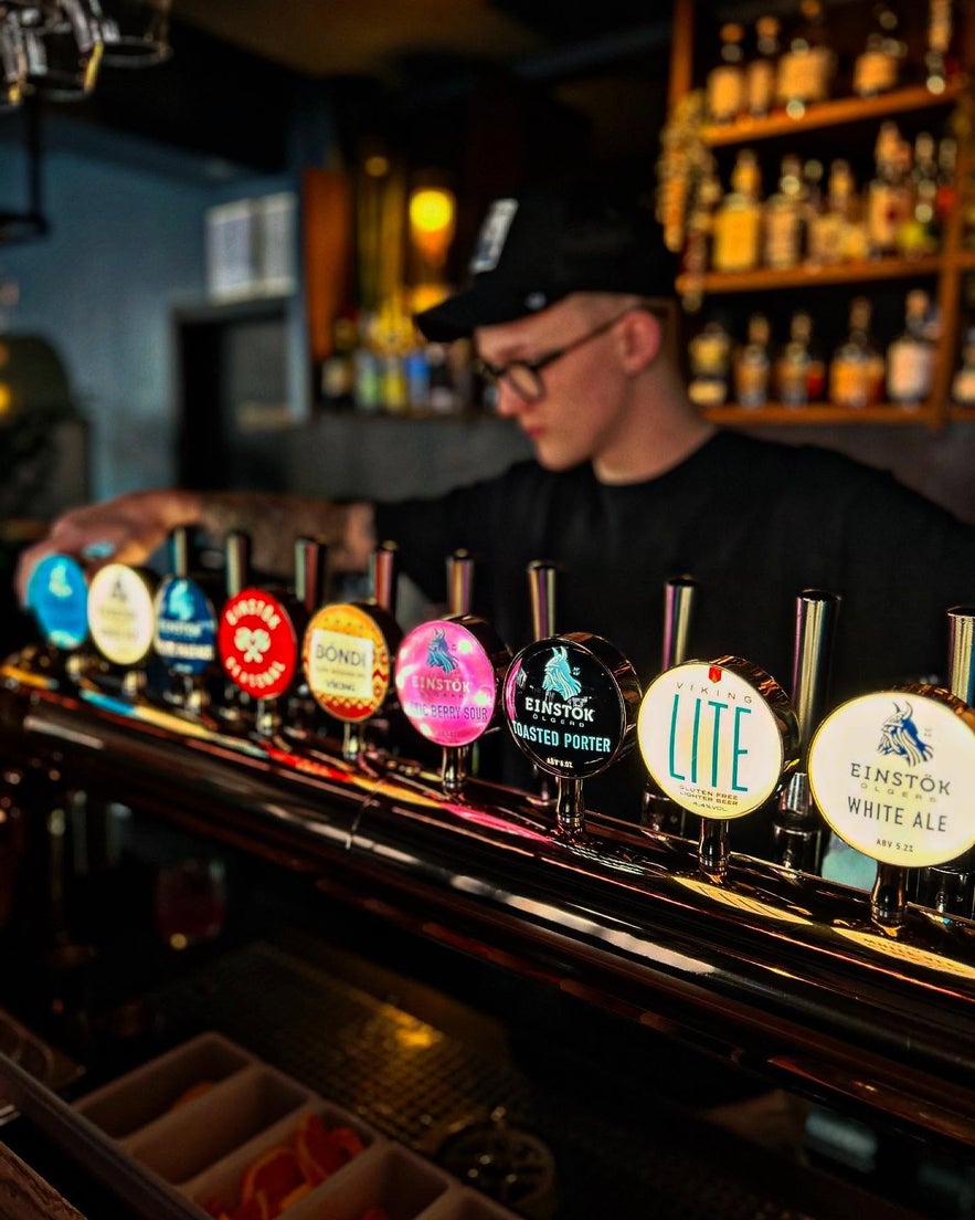 Bartender pouring craft beer from Einstok taps in Reykjavik bar.