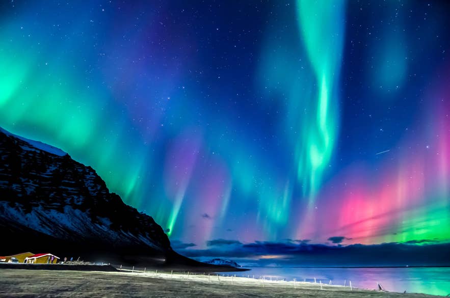Nordlichter über Bergen und Meer in Island