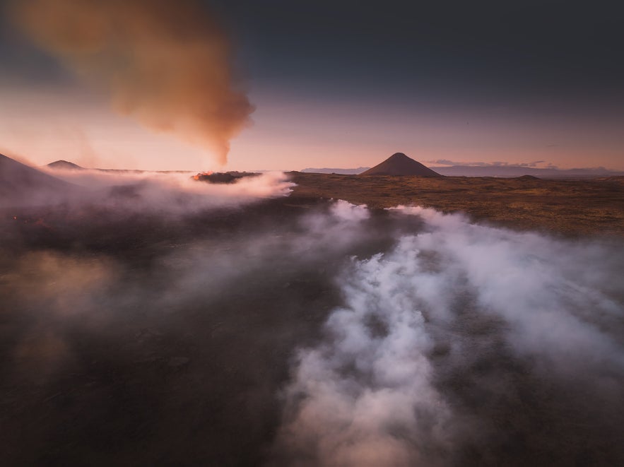 Aerial view of the Litli-Hrutur volcanic eruption on the Reykjanes Peninsula, with steaming lava and volcanic gas clouds at dusk