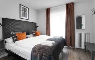 Bright bedroom at Baldur Apartments with double bed, white linens, and warm-toned decor