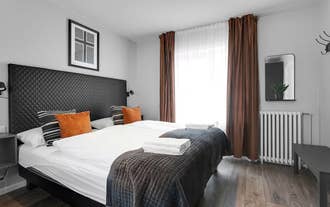 Bright bedroom at Baldur Apartments with double bed, white linens, and warm-toned decor