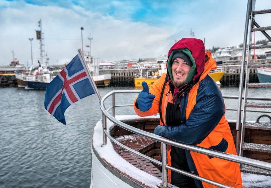 Local fisherman dressed for harsh iceland weather aboard a boat in a snowy harbor
