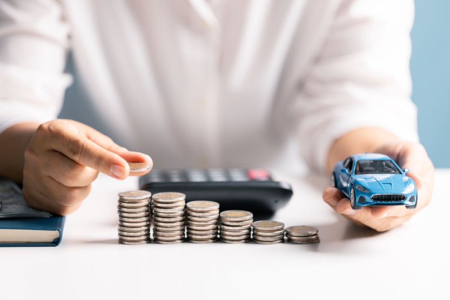 Money stacks and a toy car symbolizing living costs for Iceland population