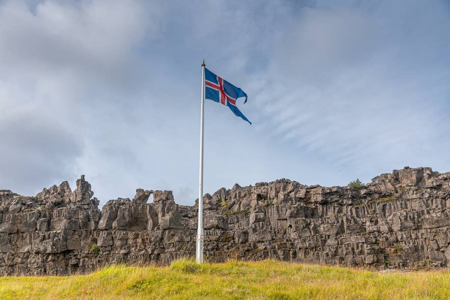 Logberg Law Rock marks the historic assembly site as the Icelandic flag waves overhead in Thingvellir National Park.