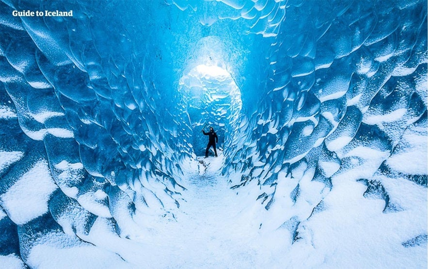 Explorer inside a blue ice cave in Vatnajokull Glacier during the cheapest time to go to Iceland.