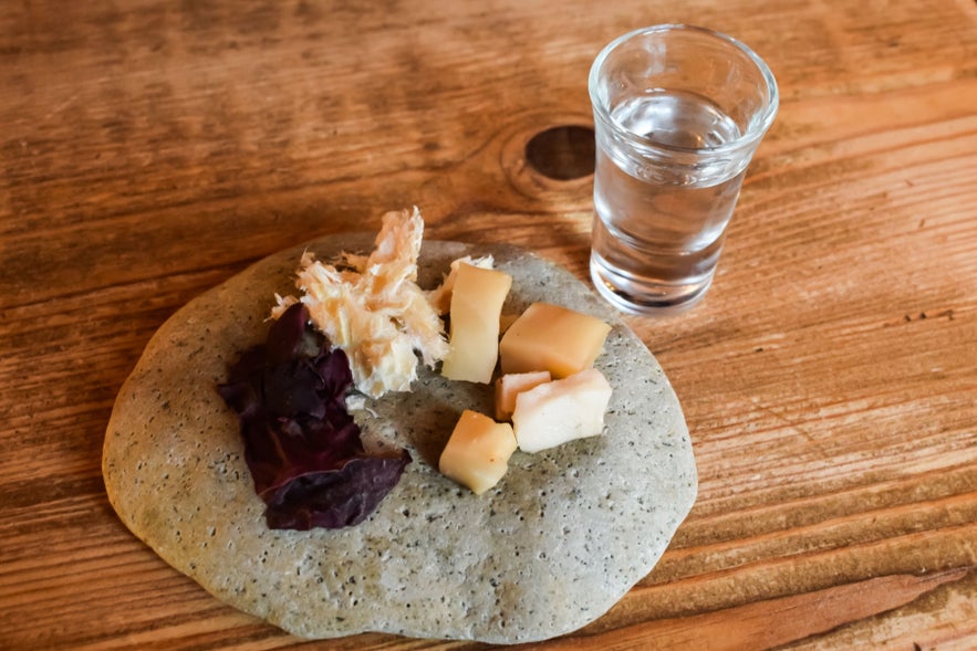 Icelandic hakarl with brennivin on stone plate, showing traditional food customs and tasting tips for how to travel in Iceland.