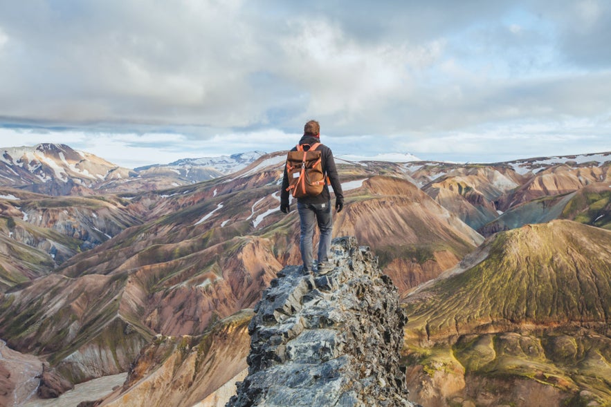 Hiker overlooking Landmannalaugar Highlands, highlighting trail safety and preparation tips for how to travel in Iceland.