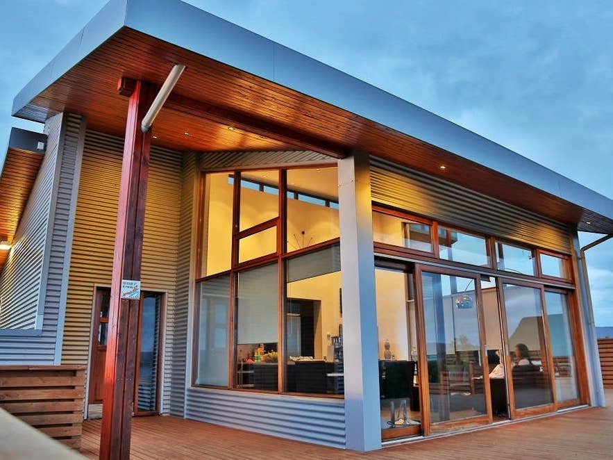 Lundur Cottage glows warmly through its glass doors and windows, creating a cozy ambience.