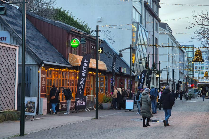 Airwaves music venue and bar in downtown Reykjavik, with people gathering along a lively street lit by festive lights.