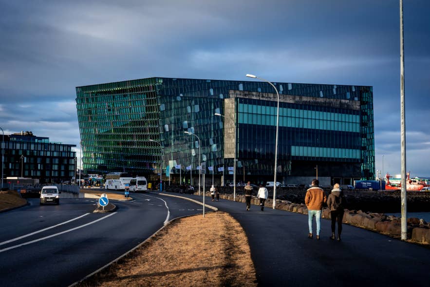 Sala Concerti e Conferenze Harpa a Reykjavik, moderno edificio in vetro sul porto con persone che passeggiano lungo il lungomare.