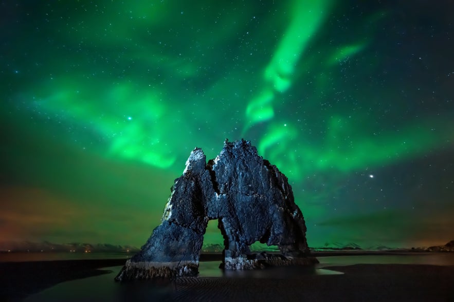 Northern Lights glowing above Hvitserkur during winter on Vatnsnes Peninsula in North Iceland.