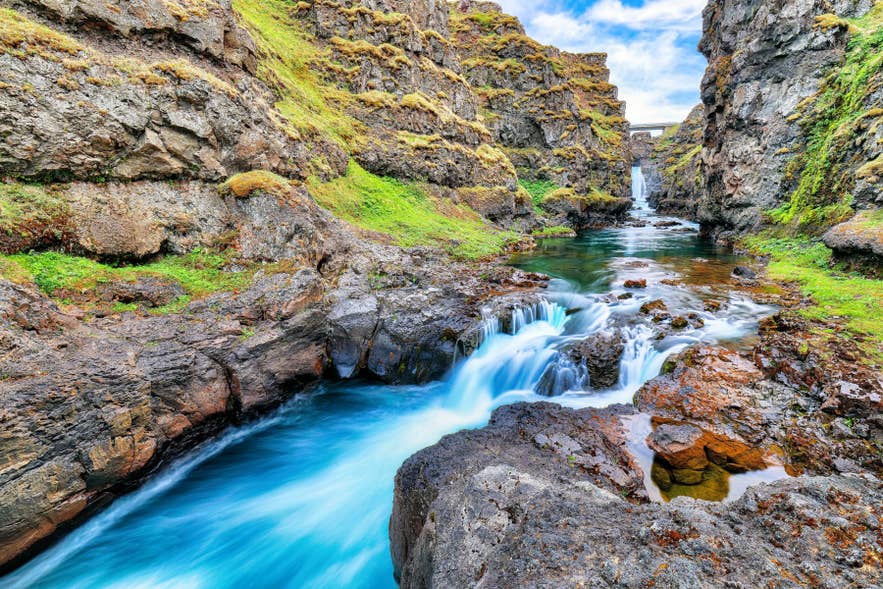 Malerische Wasserfälle fließen durch die von moosbewachsenen Klippen umgebene Schlucht Kolugljufur im Norden Islands.