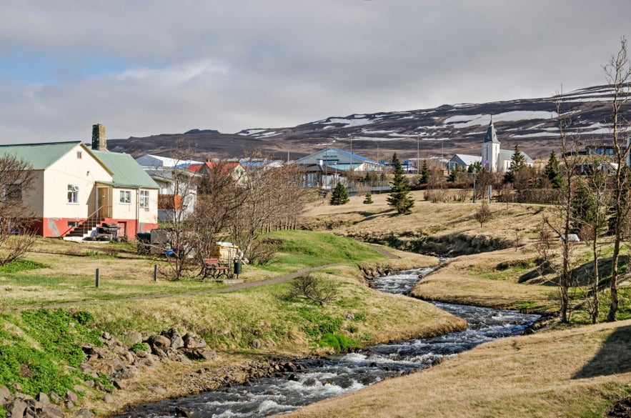 Peaceful riverside view of Hvammstangi in North Iceland with mountains in the background.