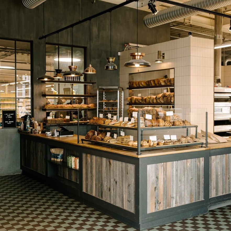 Modern rustic interior of Braud & Co in Reykjavik with pastries, sourdough loaves, and warm lighting over a wooden counter.