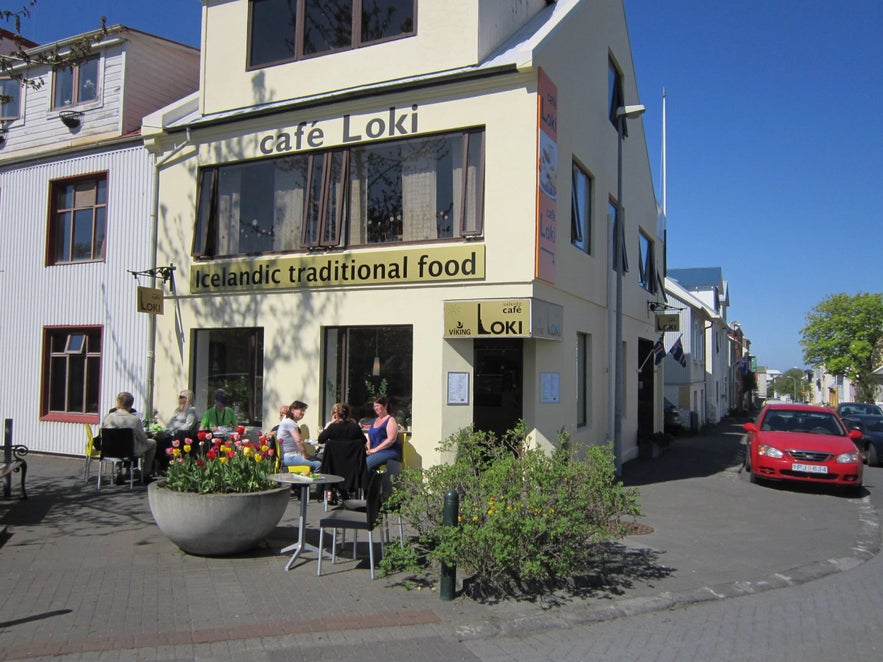 Cafe Loki on a sunny day in Reykjavik offering traditional Icelandic food with customers seated outside by a flower planter.
