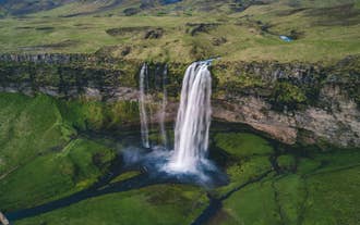 Seljalandsfoss Waterfall cascades over a green cliff along Iceland’s South Coast.