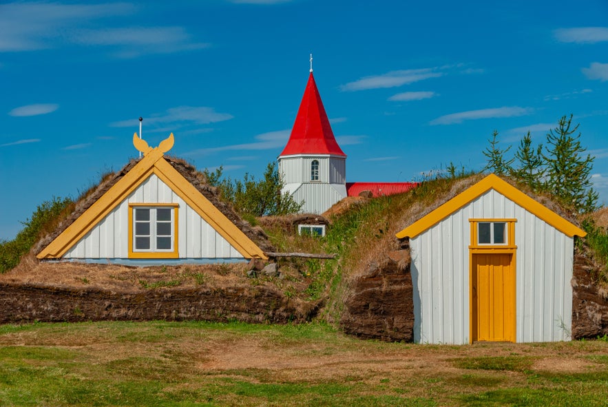 The historic Glaumbaer Turf Farm in Iceland featuring yellow-trimmed white gables and thick turf walls, showcasing 18th-century Icelandic vernacular architecture.
