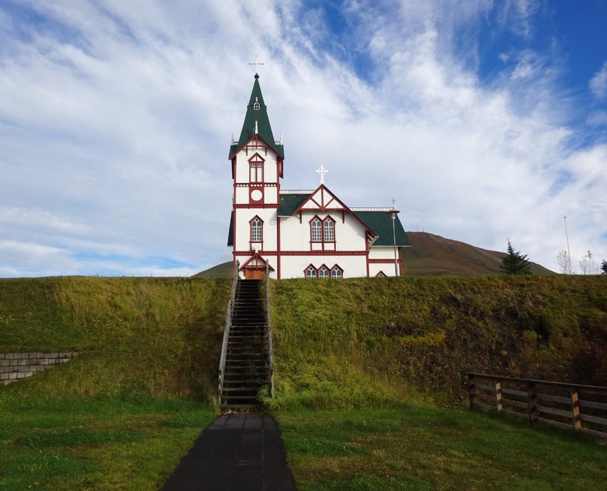 Husavikurkirkja, a unique Swiss-style wooden church in Husavik, Iceland, designed by R&ouml;gnvaldur &Oacute;lafsson with green roofing and red accents.