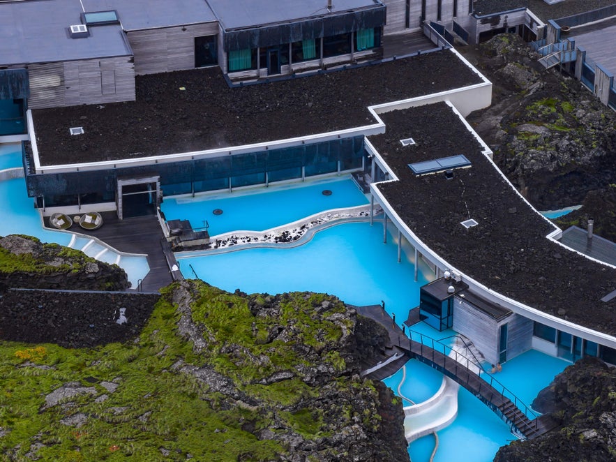 Aerial view of the Blue Lagoon Spa architecture, showing the modern hotel structure integrated into a black lava field and turquoise geothermal waters.