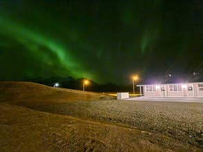 Aurora lights glowing above mountains and countryside in Iceland.