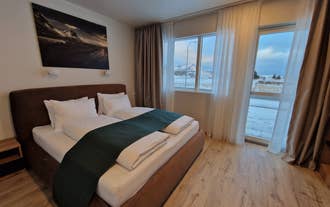 Cozy double bedroom with modern decor and mountain landscape artwork at Hofn Apartments in South Iceland.