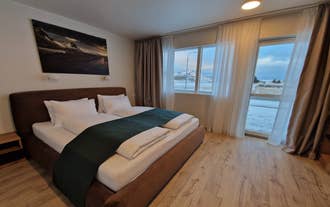 Cozy double bedroom with modern decor and mountain landscape artwork at Hofn Apartments in South Iceland.