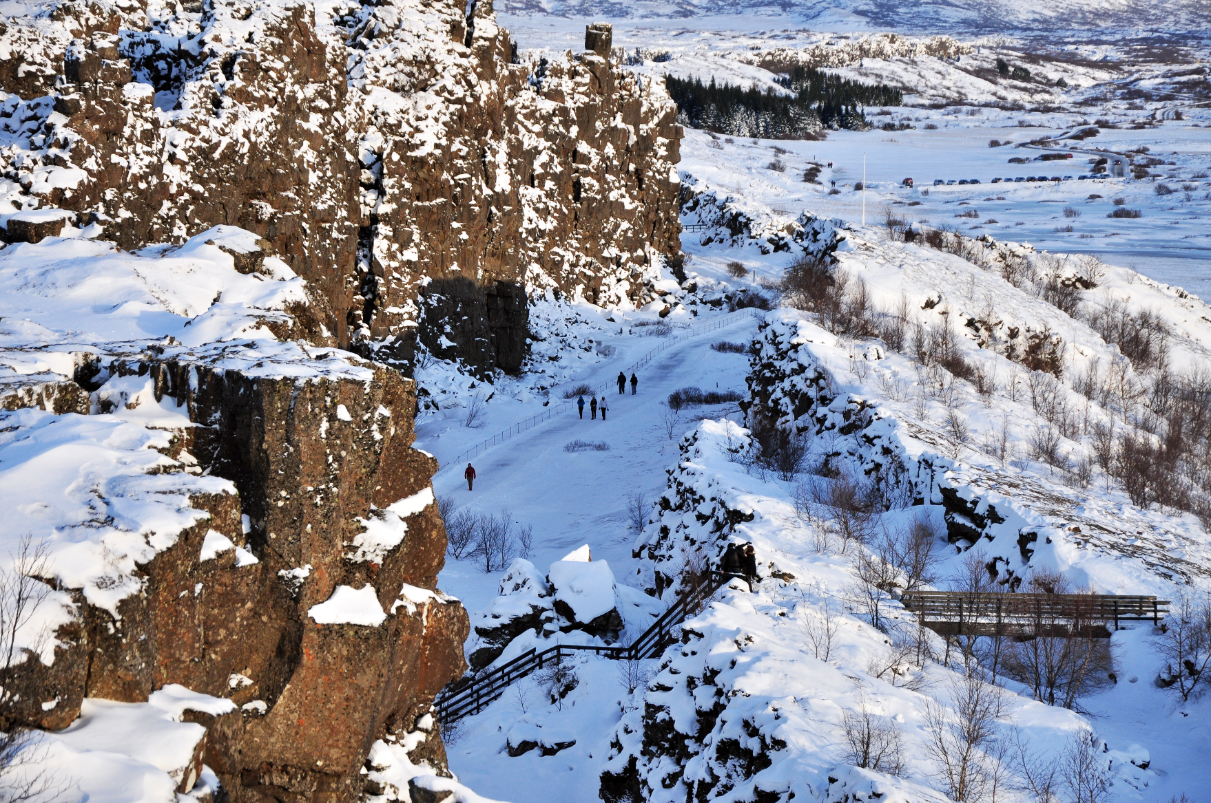 Snow-covered cliffs tower over the rift valley path at Thingvellir National Park on a Golden Circle tour.