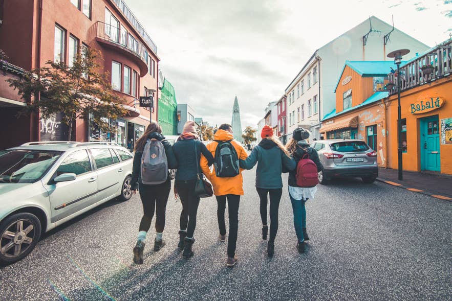 IJsland met kinderen die wandelen over Laugavegur in Reykjavik, met de kerk Hallgrimskirkja op de achtergrond.