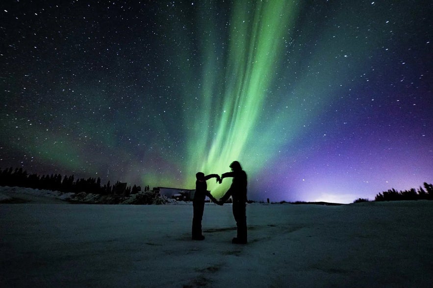 Family forming a heart under the northern lights in winter, a magical Iceland with kids experience.