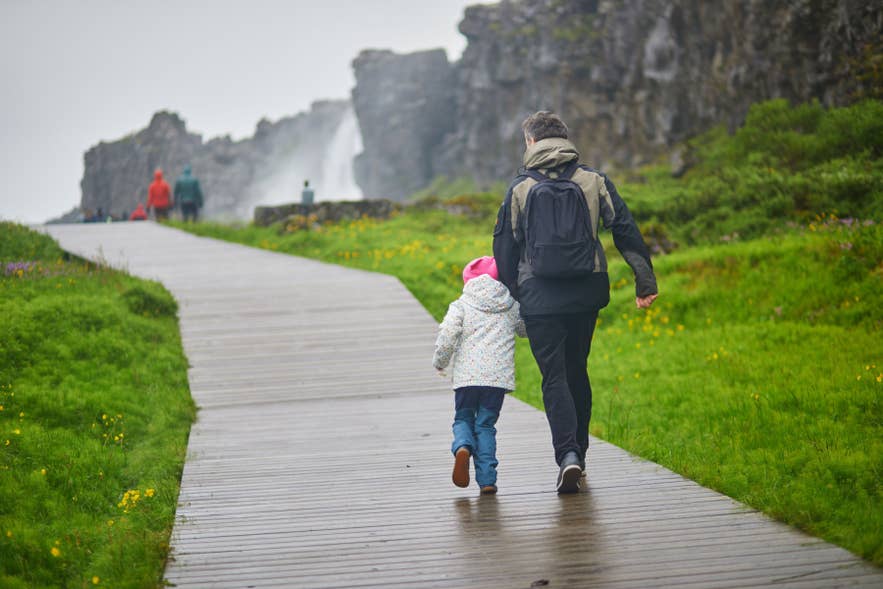 Islanda con bambini che passeggiano sulle passerelle del Parco Nazionale di Thingvellir vicino alla cascata Oxararfoss.