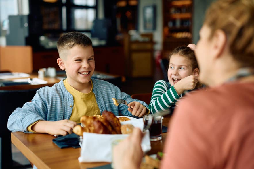 Famiglia che si gode un pasto in un ristorante di Reykjavik, per un’esperienza gastronomica rilassata in Islanda con bambini.