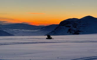 Two riders sharing a snowmobile during snowmobiling in Langjokull Glacier heading to the sunset.