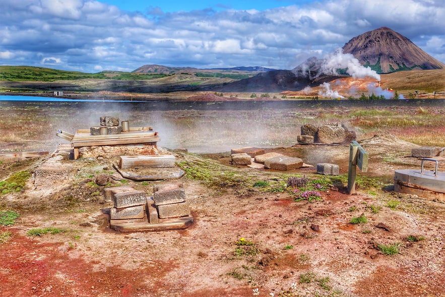 Stone steam vents and geothermal cooking area near Hverir and Lake Myvatn in North Iceland, with fumaroles and volcanic hills in the background.