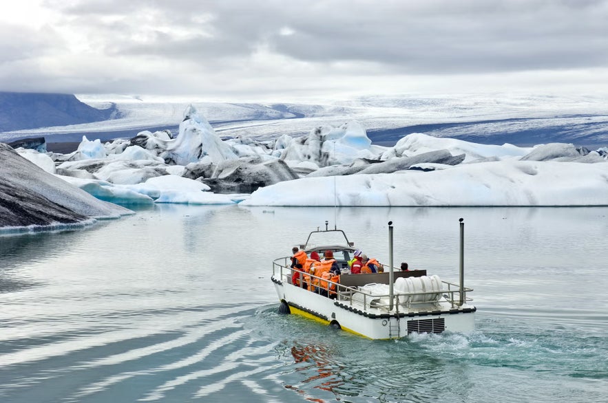 Visitors on a zodiac boat at Jokulsarlon Glacier Lagoon, surrounded by icebergs and calm glacial waters.