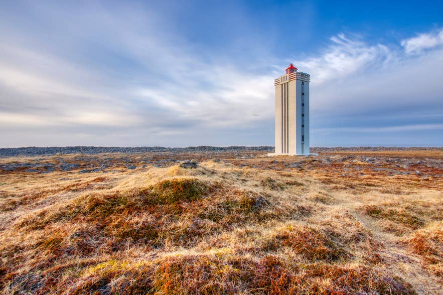 Hraunhafnartangi Lighthouse standing on a rocky coastal plain near Raufarhofn in North Iceland under a wide blue sky.