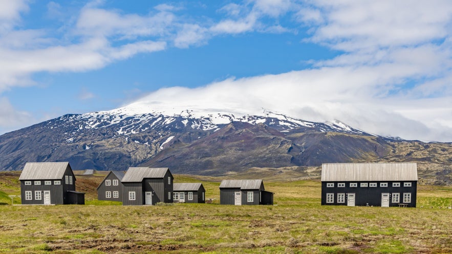 Traditional black wooden houses with Snaefellsjokull glacier rising in the background on the Snaefellsnes Peninsula. Traditional black wooden houses with Snaefellsjokull glacier rising in the background on the Snaefellsnes Peninsula.