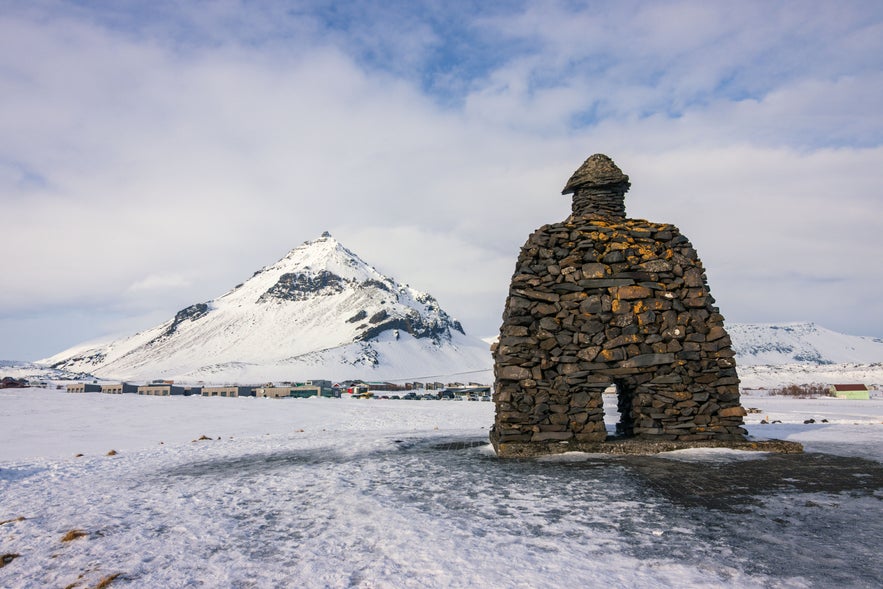 Stone sculpture overlooking snow covered mountains near Arnarstapi on the Snaefellsnes Peninsula. Stone sculpture overlooking snow covered mountains near Arnarstapi on the Snaefellsnes Peninsula.