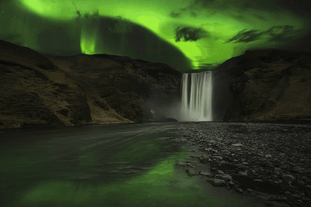 Mesmerizing northern lights gracefully dance over the majestic Skogafoss waterfall, creating a truly enchanting spectacle.