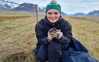 A traveler holds a small bird while learning about local wildlife on an Isafjordur day tour in the Westfjords.